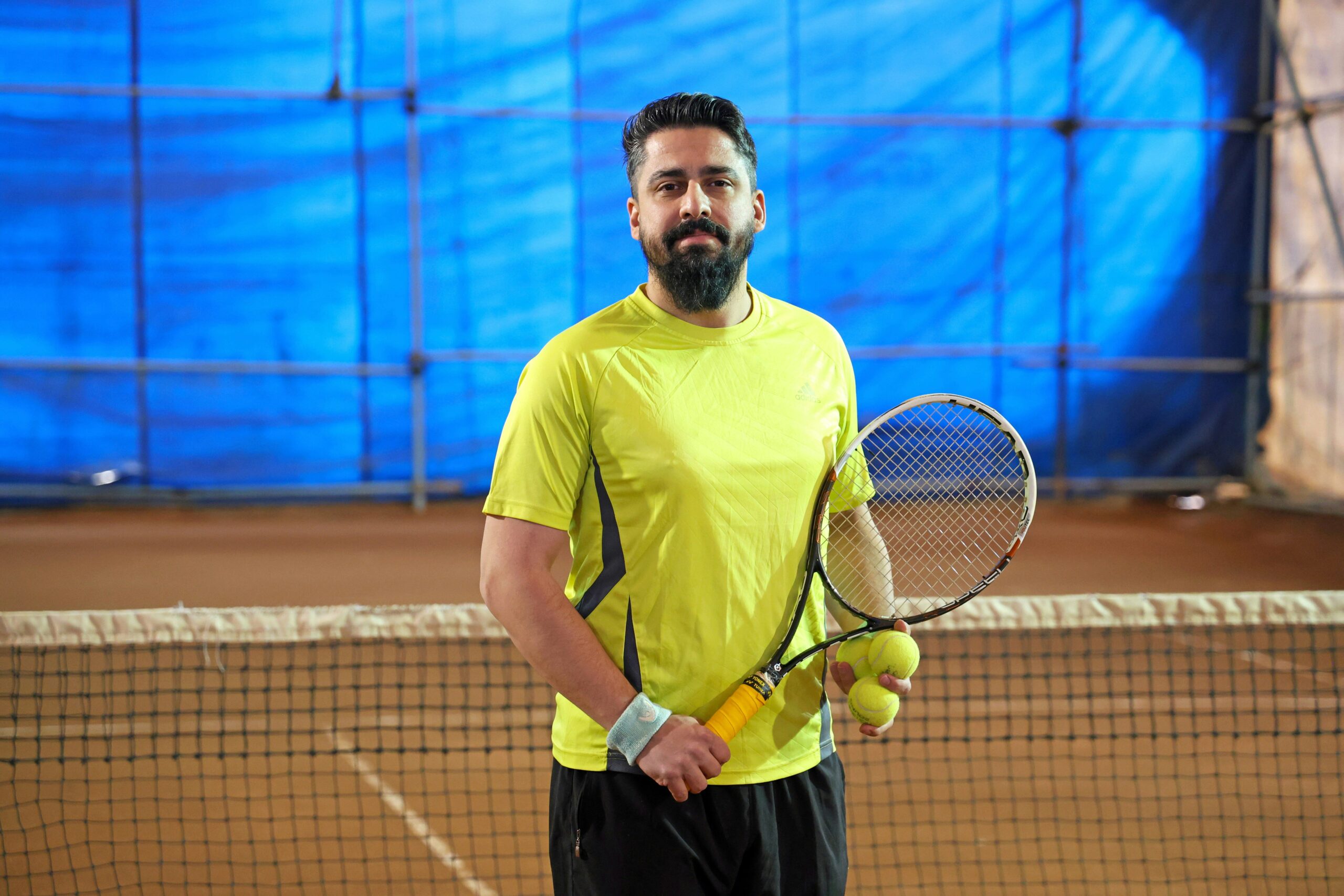 Man with tennis racket and balls on court