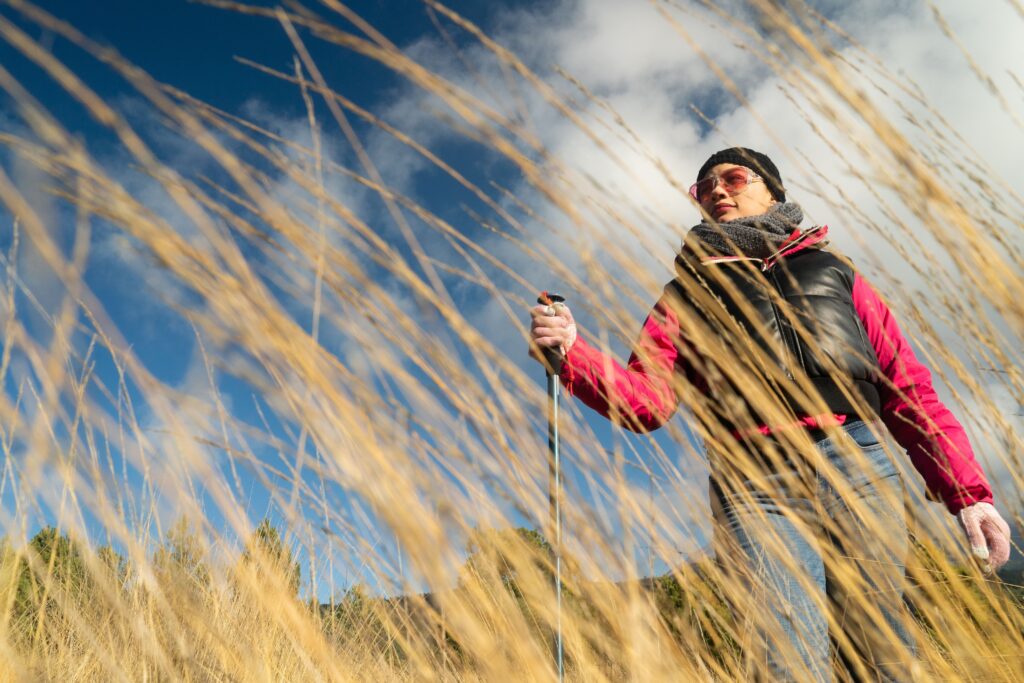 Donna in mezzo all'erba con i bastoni di nordic walking