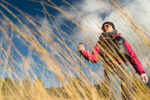 Donna in mezzo all'erba con i bastoni di nordic walking