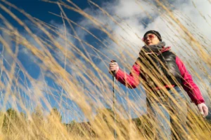 Donna in mezzo all'erba con i bastoni di nordic walking