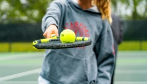 Una ragazza che tiene una pallina sopra la racchetta da tennis