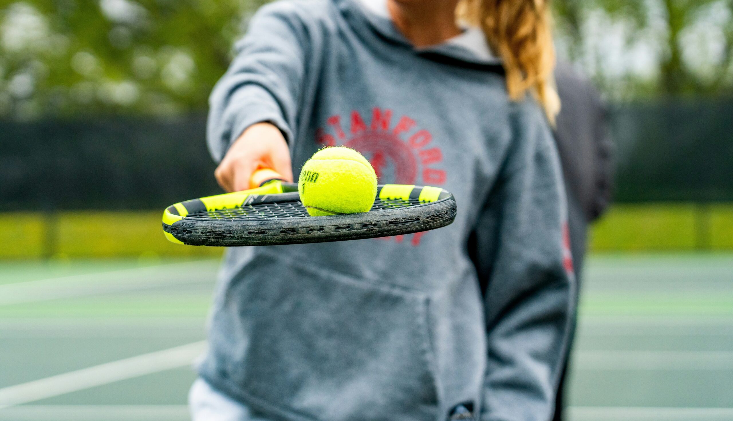Una ragazza che tiene una pallina sopra la racchetta da tennis